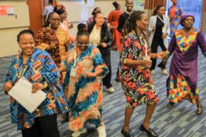 African feminists in their diverse cultural attire dancing at the conference hall way.