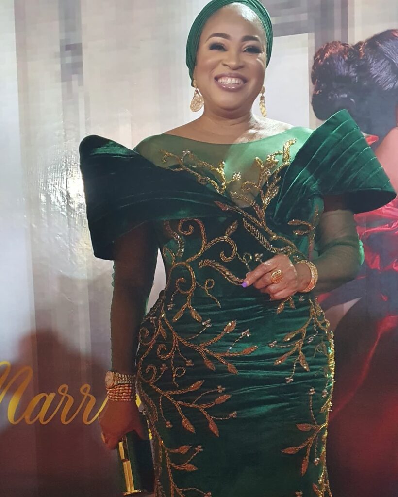 Bukky wearing an emerald gown with golden intricate designs.