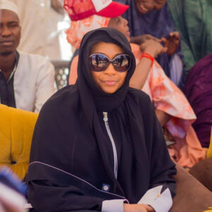 Hadiza Abubakar Yaradua in a black gown wearing a black shade covering her eyes sitting.