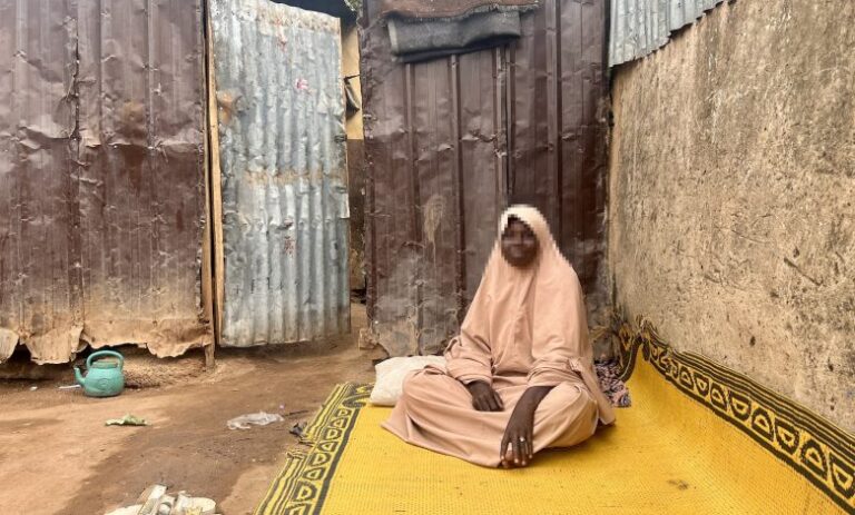 Hadiza Aliyu sits in front of her home in an IDP Camp. Photo: HumAngle.