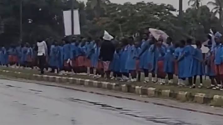A screenshot from a video of the school children in the rain.
