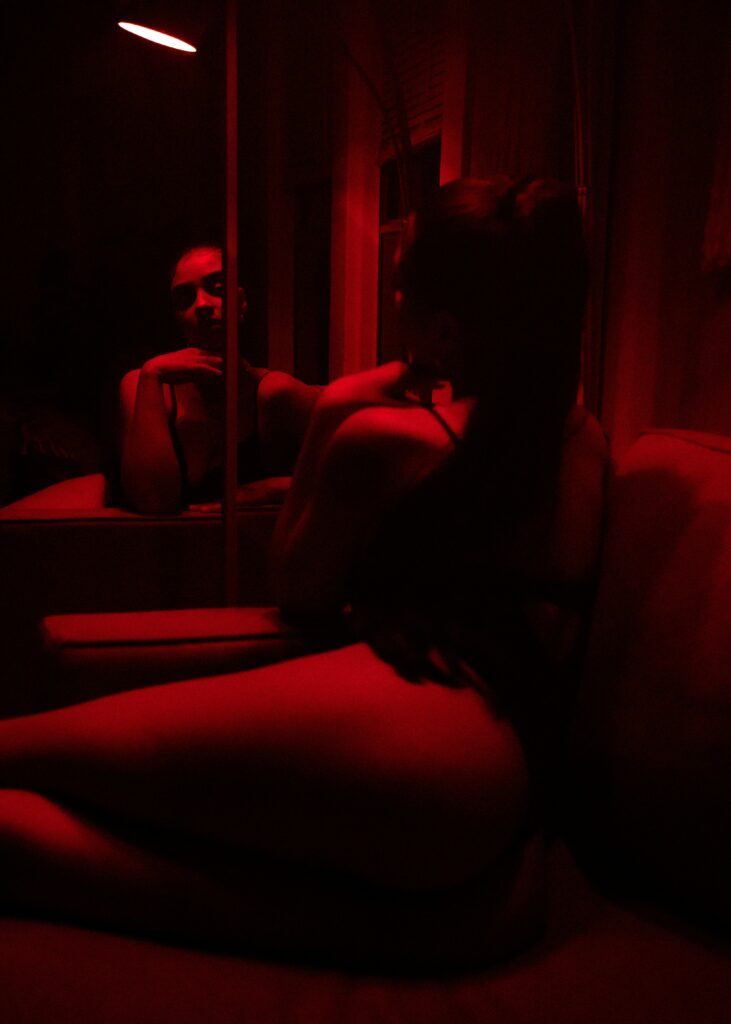 Woman sitting on a chair facing a mirror. Photo by kevin turcios on Unsplash